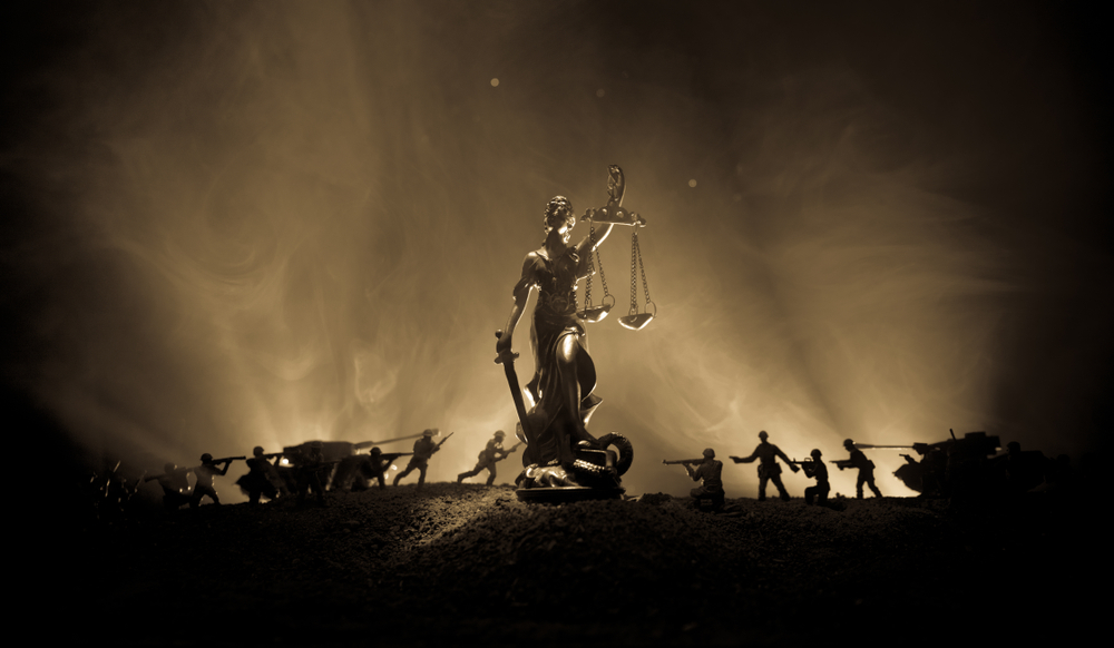 War - no justice concept. Military silhouettes fighting scene and The Statue of Justice on a dark toned foggy background.