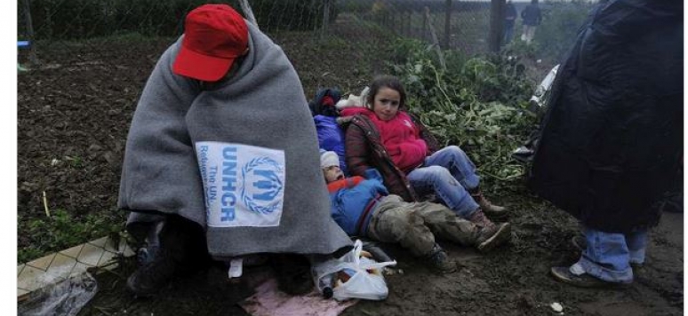 A refugee trying to keep warm at the border between Serbia and Croatia.