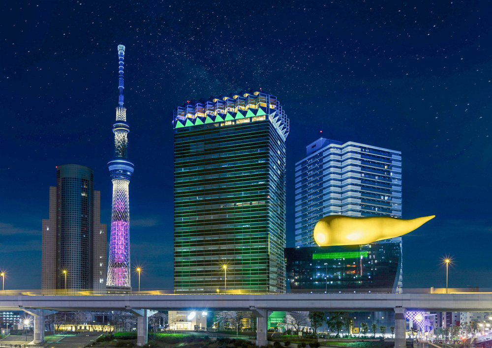 Tokyo, Japan - March 25, 2020: Night view of the illuminated Japan tallest tower Tokyo Skytree and the Olympic golden flame shape sculpture by Stark for the Asahi Beer Headquarter Building in Asakusa. 