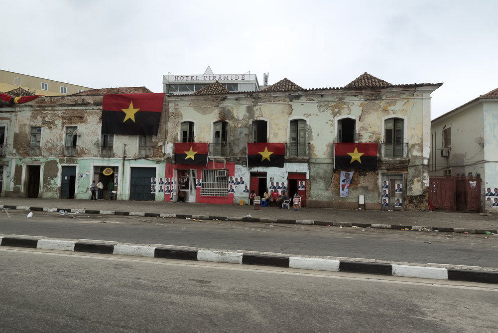 Residents sit outside on election day in Angola underneath the flags of the ruling People's Movement for the Liberation of Angola (MPLA) party, on 23 August 2017